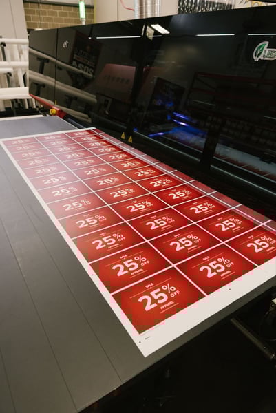 Large format retail sign printing of 25 percent off promotional sale signs on a commercial printer