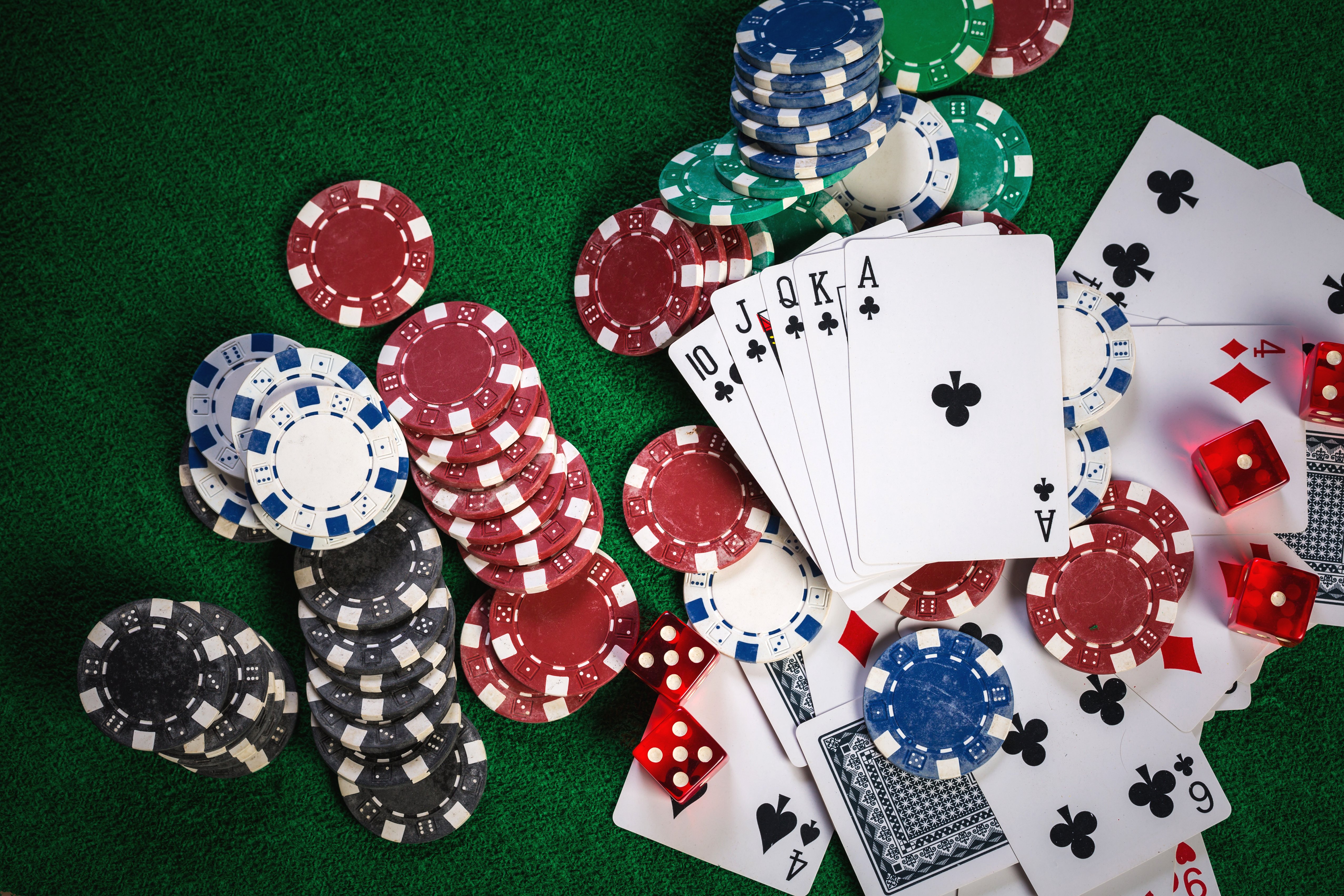 Poker chips, playing cards, and dice on a green casino table.