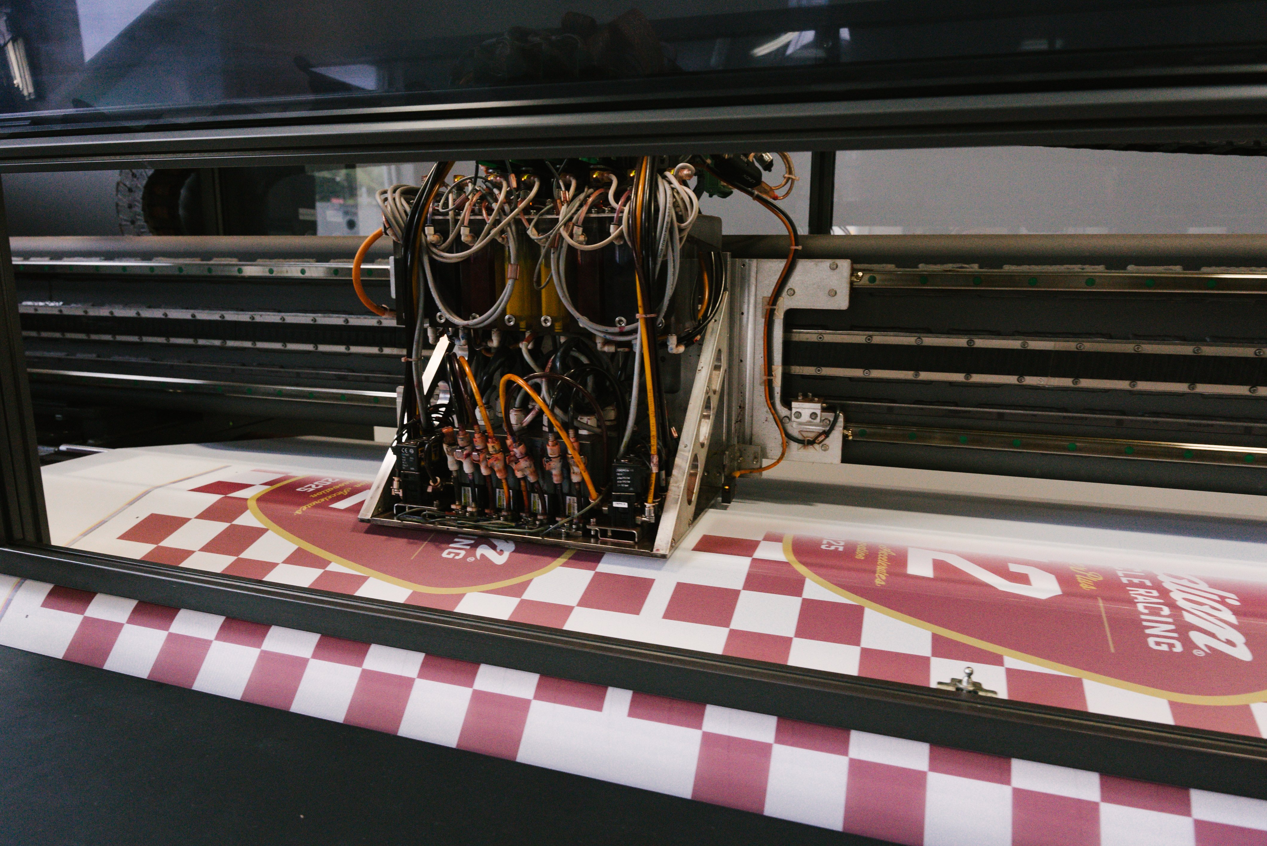 Large-format printer producing red-and-white signage.