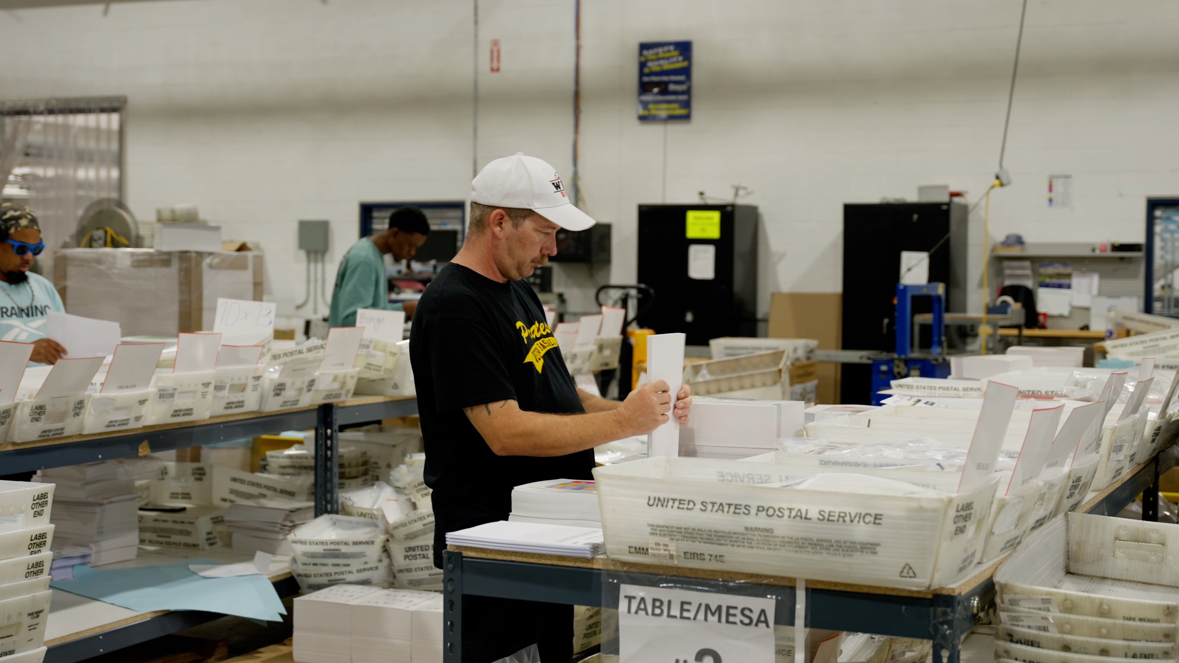Worker sorts printed mail in a production facility.